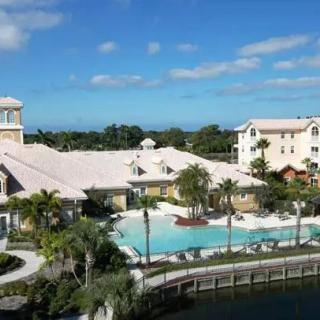 A luxurious resort featuring a large pool surrounded by palm trees and elegant architecture.