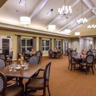 A spacious dining room with elegant chandeliers and neatly arranged tables and chairs.