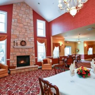 A cozy living room with a fireplace and adjacent dining area, featuring elegant furnishings and high ceilings.