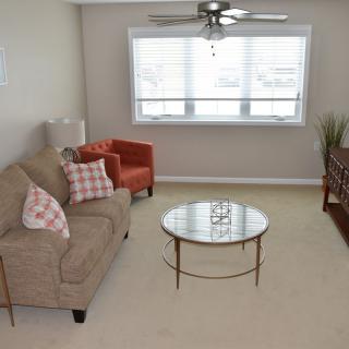 A cozy living room with a sofa, armchair, and coffee table under a ceiling fan.