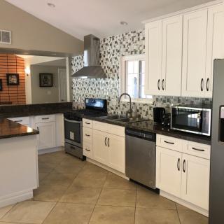 A modern kitchen with white cabinets, stainless steel appliances, and a decorative backsplash.