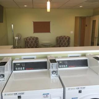 A view of a laundry room featuring washing machines and a cozy waiting area.