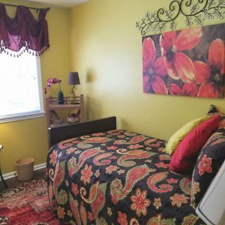 A colorful bedroom with floral decorations, featuring a single bed and artwork on the wall.