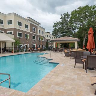 Outdoor swimming pool area at an apartment complex with seating and umbrellas.