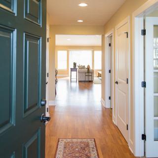 A welcoming entryway with a view into a sunlit living area featuring wooden floors and neutral wall colors.