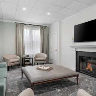 A modern living room with a cozy fireplace, television, and neutral-toned furniture.