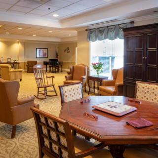 A cozy and well-lit living room with multiple seating areas, a large table, and comfortable armchairs.