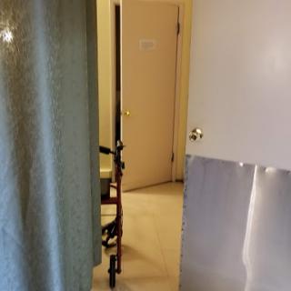 A view into a bathroom featuring a walker and a curtain.