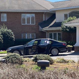 A sleek black car parked in a residential driveway next to a brick house.