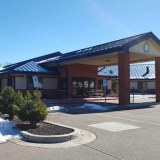 A modern commercial building with a blue roof and clear sky in the background.