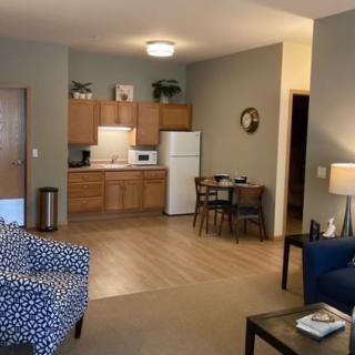 A cozy apartment interior with an open-plan living room and kitchen area, featuring comfortable furniture and warm lighting.