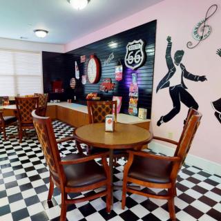 A retro-themed diner featuring rock and roll wall art and a classic black-and-white checkered floor.