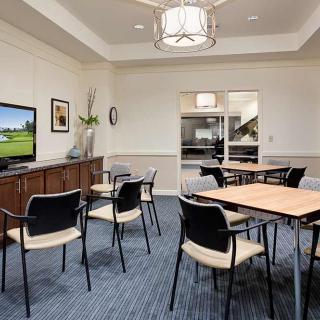 A modern meeting room with tables, chairs, and a television.