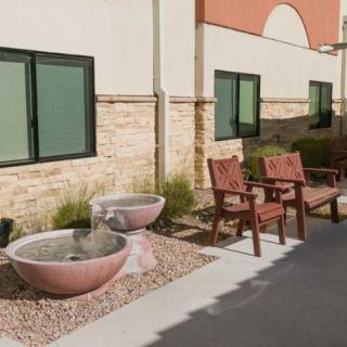 A peaceful outdoor patio area featuring a pair of fountains and wooden chairs beside a building.