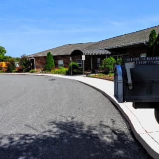A serene residential scene featuring a curved road leading to a well-maintained home with a mailbox in the foreground.