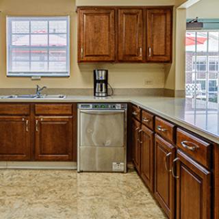 A modern kitchen with wooden cabinets, a coffee maker, and a tiled floor.
