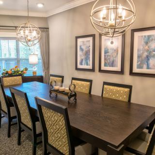 A stylish dining room with a large wooden table, elegant chairs, and decorative chandeliers.