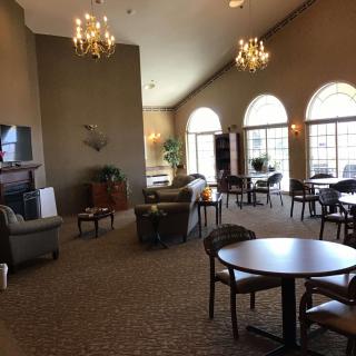 A spacious and elegant lounge area with comfortable seating, large windows, and chandeliers.