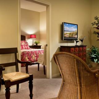 A cozy living area with a view into a well-decorated bedroom.