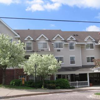 A multi-story residential building with trees in front, set against a blue sky.
