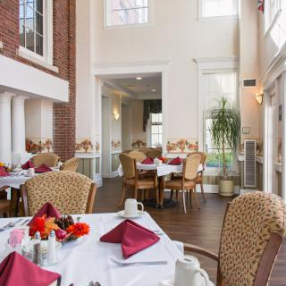 A well-lit restaurant dining area with tables neatly set for patrons, featuring elegant decor and large windows.