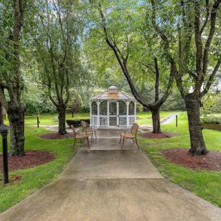 A serene garden path leads to a charming gazebo surrounded by lush trees.