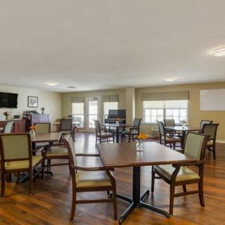 A spacious dining area with wooden floors, tables, and chairs.