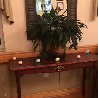 A decorative table with a plant and colorful Easter eggs.