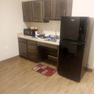 A view of a compact kitchen featuring dark cabinets, a black refrigerator, and a well-organized countertop.