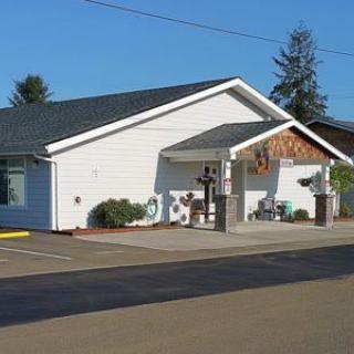 A small building with a storefront and parking lot on a sunny day.
