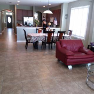 An open-concept living and dining area with a red chair and a kitchen in the background.