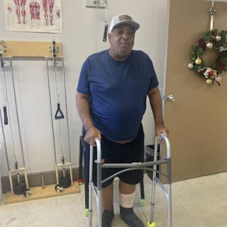 An elderly man using a walker during a rehabilitation session.