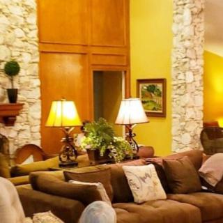 A cozy living room with warm lighting, featuring a brown couch, decorative lamps, and stone walls.