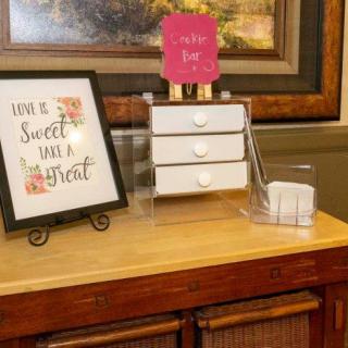 A home vanity setup with a framed inspirational sign and a clear makeup organizer.