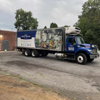 A blue refrigerated delivery truck parked in an industrial area.