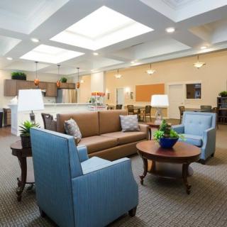 A cozy and well-lit living room with a sofa, armchairs, and a coffee table under skylights.