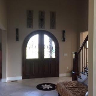 Elegant entryway featuring an arched wooden door and staircase.