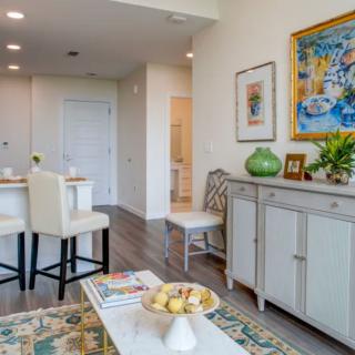 A modern living room with minimalist decor featuring a dining area and colorful artwork.