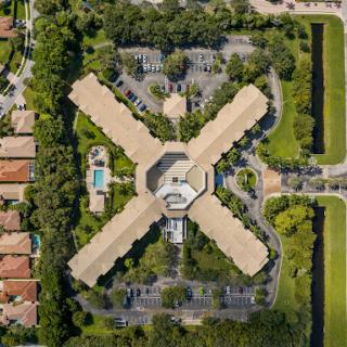 Aerial view of a residential complex featuring an intricate geometric layout surrounded by greenery.