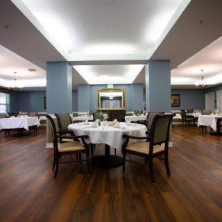 An elegant dining room with neatly arranged tables and chairs, featuring a wooden floor and modern interior design.