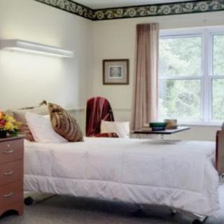 A tidy hospital room with a single bed and tray, featuring a window and decorative elements.