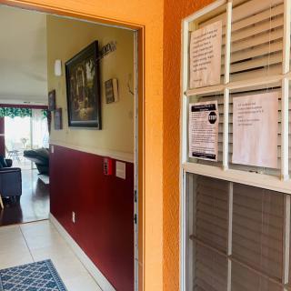 A home entryway with a window displaying various notices and a glimpse into the living room.