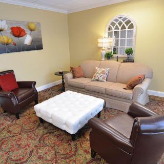 A cozy living room with a beige sofa, two brown armchairs, and a white coffee table.