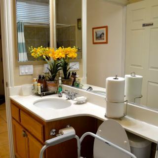 A neatly organized bathroom with a sink, mirror, and decorative flowers.