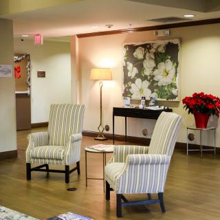 A cozy lobby area with striped chairs, a lamp, and floral decor.