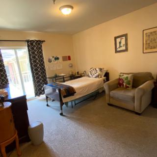 A cozy bedroom with a bed, couch, and large window with curtains.
