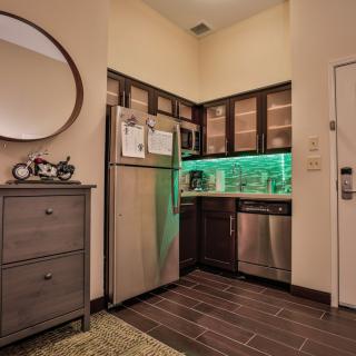 A modern kitchen in an apartment featuring stainless steel appliances and ambient green lighting.