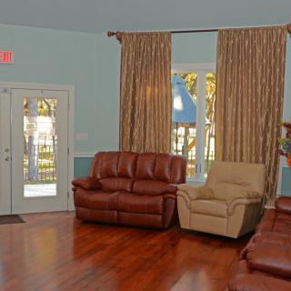 A cozy living room with leather sofas and armchairs, featuring large curtains and a wooden floor.