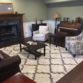 A cozy living room featuring a fireplace, armchairs, and a piano.