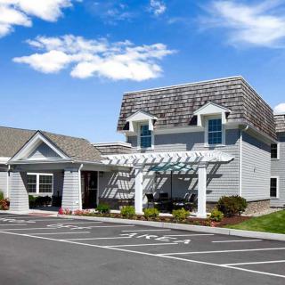 A hotel exterior with a parking lot and clear blue sky.